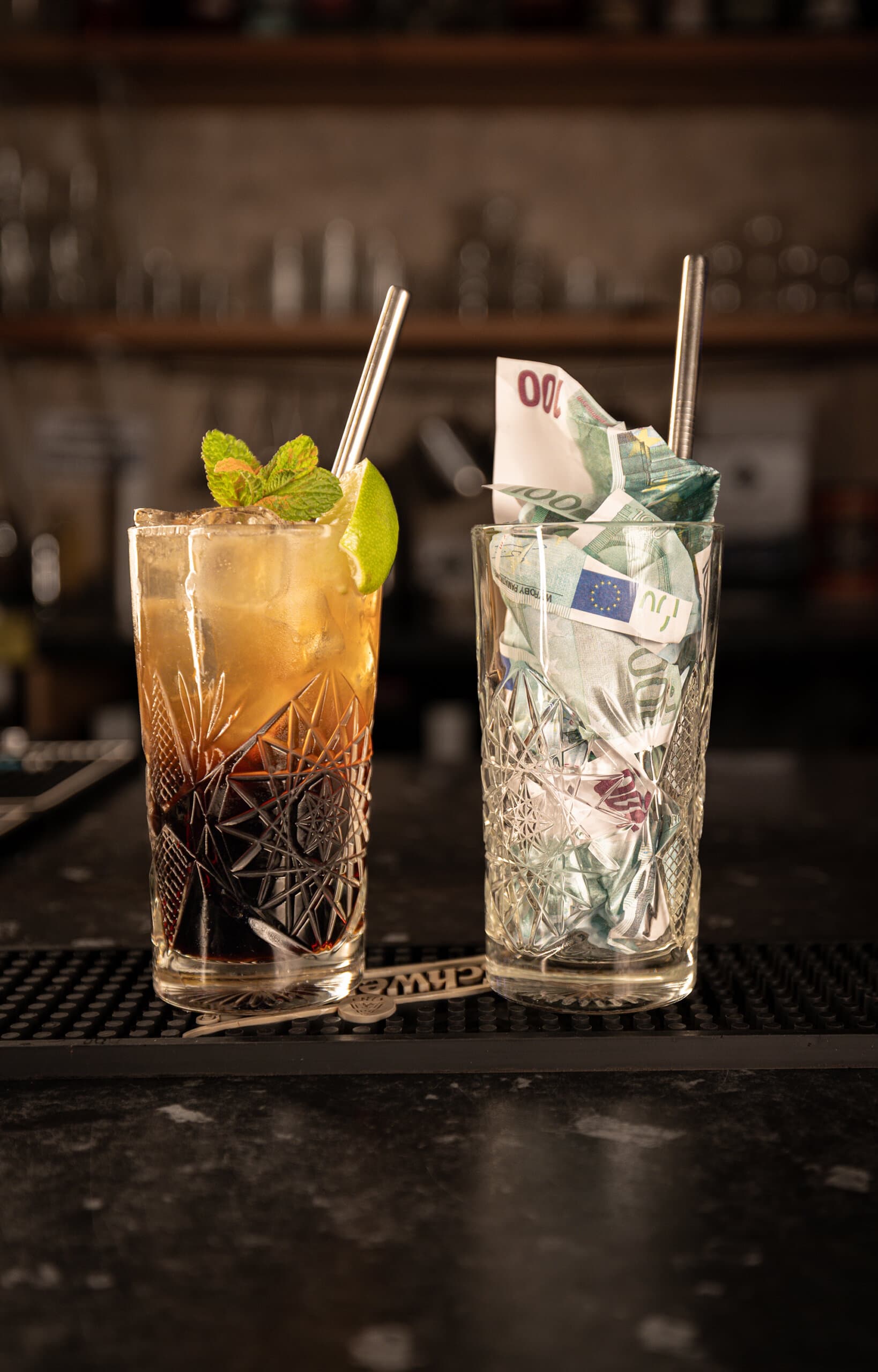 A cocktail beside a glass packed with banknotes